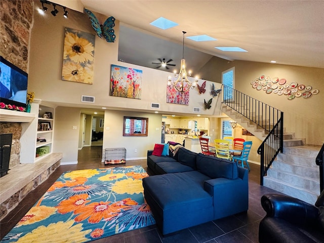 living room with a skylight, visible vents, a premium fireplace, stairs, and a notable chandelier