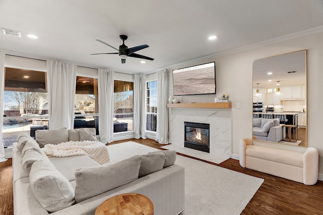 living area featuring dark wood-style floors, a wealth of natural light, visible vents, and a fireplace