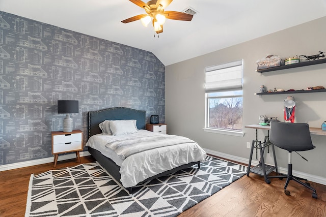 bedroom with wallpapered walls, baseboards, lofted ceiling, an accent wall, and wood finished floors