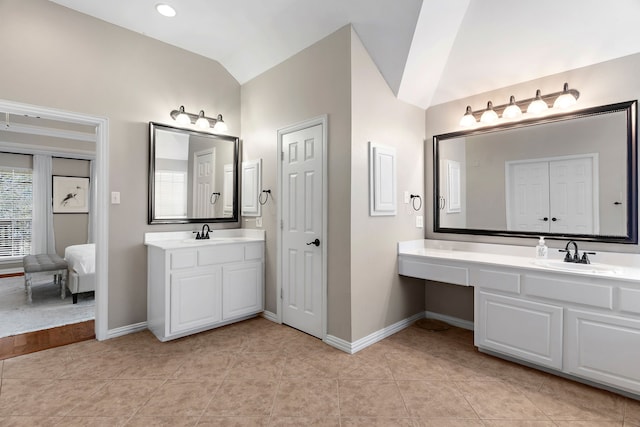 bathroom featuring lofted ceiling, two vanities, a sink, and ensuite bathroom