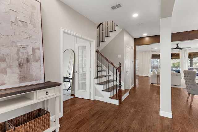 foyer featuring stairs, dark wood finished floors, visible vents, and baseboards