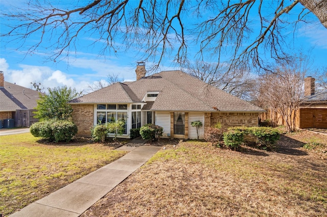 view of front of home featuring a chimney, roof with shingles, fence, a front yard, and brick siding