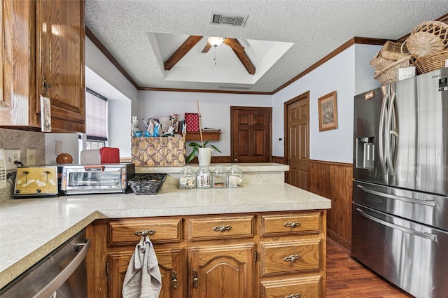 kitchen featuring a wainscoted wall, visible vents, light countertops, appliances with stainless steel finishes, and brown cabinetry