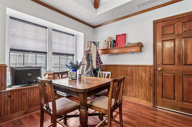 dining space featuring a textured ceiling, ornamental molding, wainscoting, and dark wood finished floors