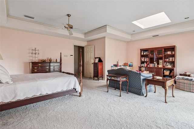 bedroom with light carpet, a skylight, visible vents, a raised ceiling, and ornamental molding