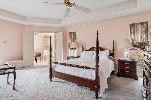 bedroom with a textured ceiling, carpet flooring, ornamental molding, multiple windows, and a tray ceiling