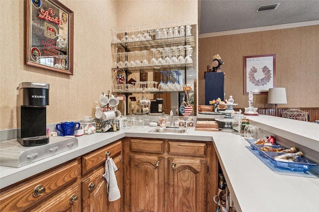 kitchen featuring brown cabinets, visible vents, light countertops, and ornamental molding