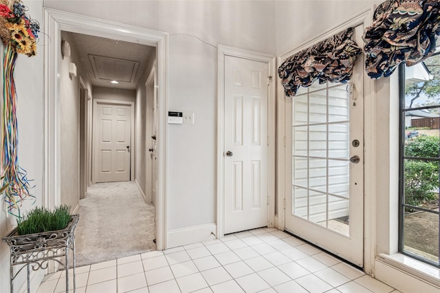 doorway to outside featuring light colored carpet, light tile patterned flooring, and baseboards