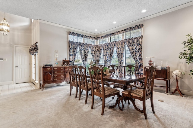 dining room featuring a textured ceiling, ornamental molding, baseboards, and light colored carpet