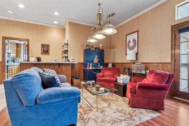 living area featuring ornamental molding, recessed lighting, wainscoting, and wood finished floors