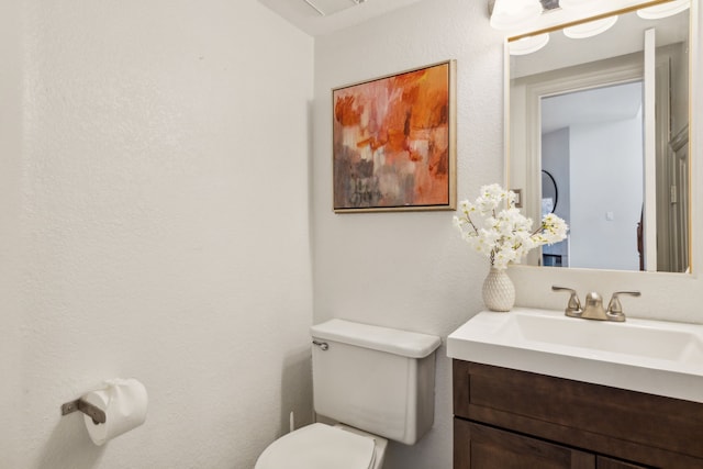 bathroom with toilet, a textured wall, and vanity