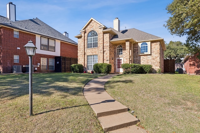 traditional-style house featuring a chimney, central AC unit, a front lawn, and brick siding