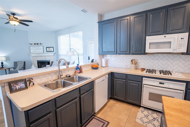 kitchen with light tile patterned floors, a peninsula, white appliances, a sink, and open floor plan