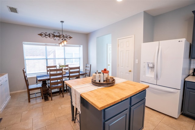 kitchen with visible vents, a center island, decorative light fixtures, light countertops, and white fridge with ice dispenser