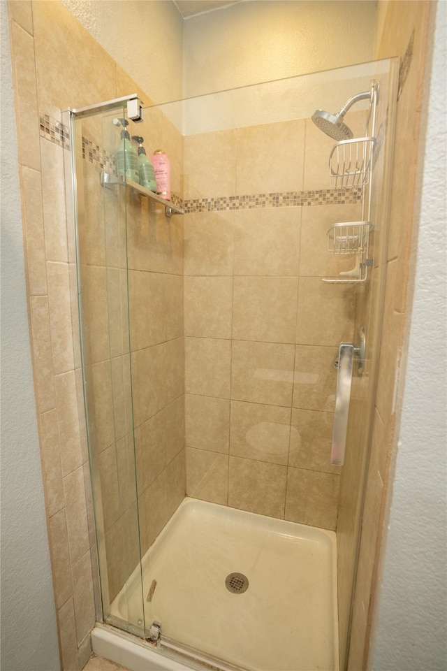 bathroom with a textured wall and a stall shower