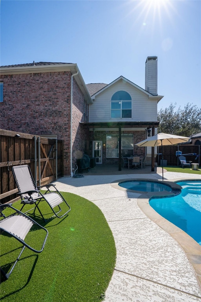 back of property with brick siding, fence, a fenced in pool, a chimney, and a patio area