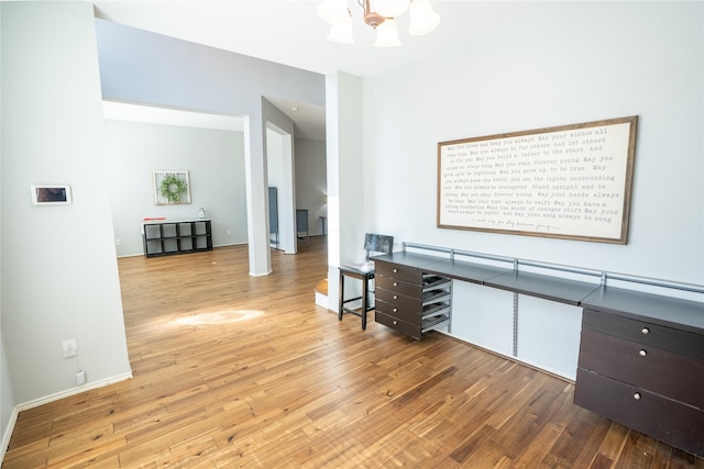 interior space with baseboards, wood finished floors, and an inviting chandelier