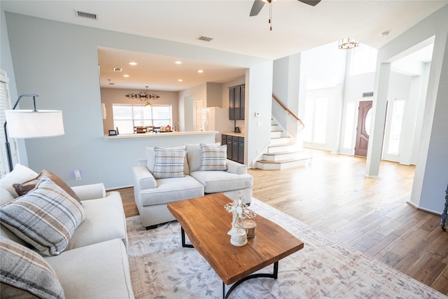 living room featuring light wood finished floors, stairs, visible vents, and recessed lighting