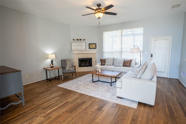 living room featuring a fireplace, dark wood finished floors, and a ceiling fan