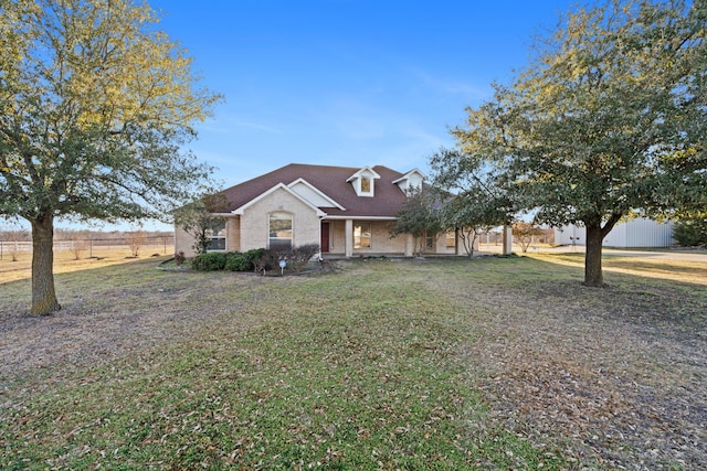 view of front of house featuring brick siding, a front yard, and fence