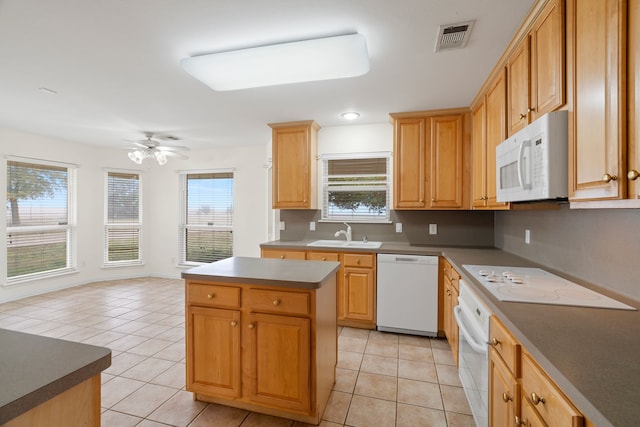 kitchen with white appliances, light tile patterned floors, a sink, and a center island