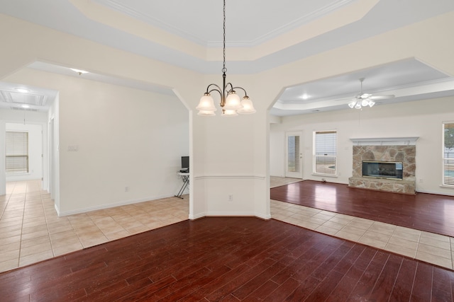 interior space with attic access, a raised ceiling, light wood-type flooring, a fireplace, and a wealth of natural light