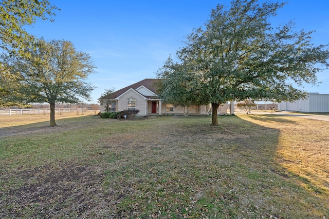 view of front of property with a rural view, fence, and a front lawn