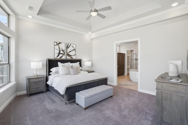 bedroom featuring baseboards, visible vents, connected bathroom, a tray ceiling, and dark colored carpet