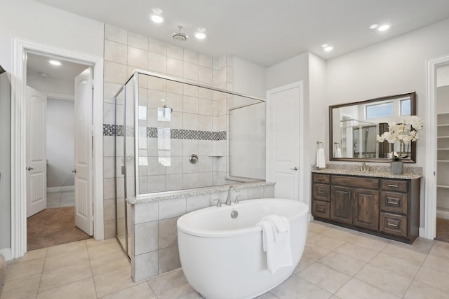 full bathroom with recessed lighting, a shower stall, vanity, a freestanding tub, and tile patterned floors