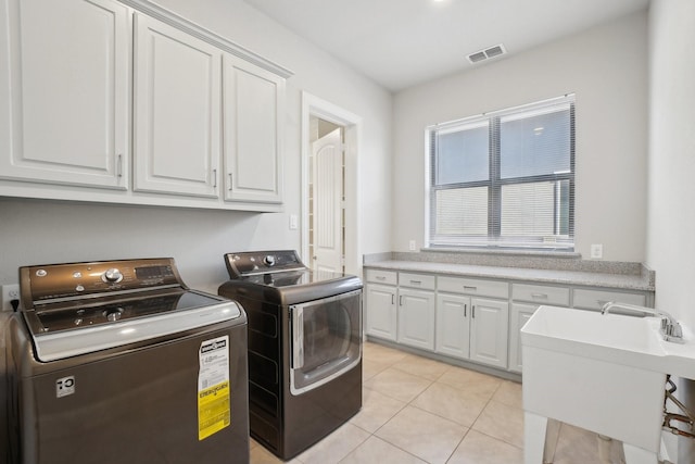 laundry area featuring washer and clothes dryer, light tile patterned floors, visible vents, cabinet space, and a sink