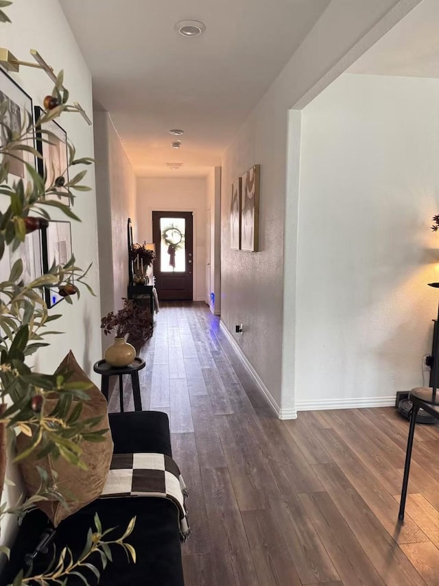 corridor with baseboards and wood finished floors