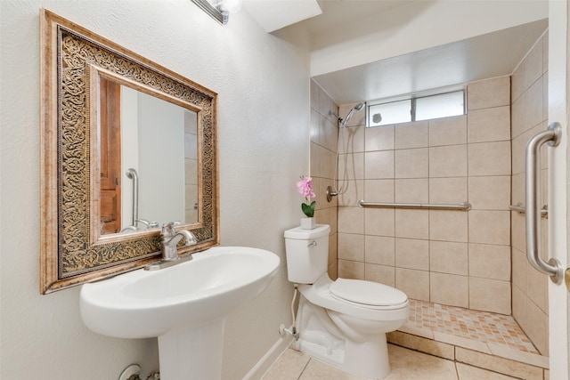 full bathroom featuring tiled shower, a sink, toilet, and tile patterned floors