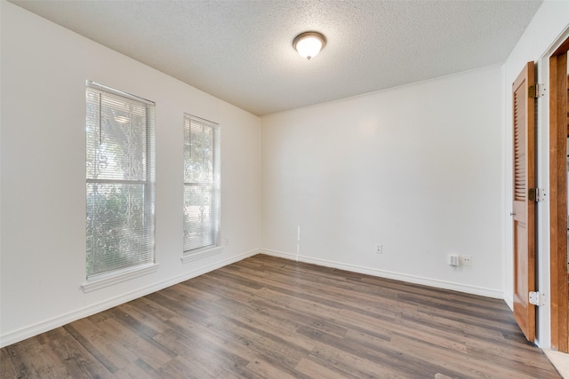 unfurnished room featuring a textured ceiling, dark wood-style flooring, and baseboards