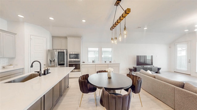 kitchen featuring light countertops, backsplash, appliances with stainless steel finishes, open floor plan, and a sink