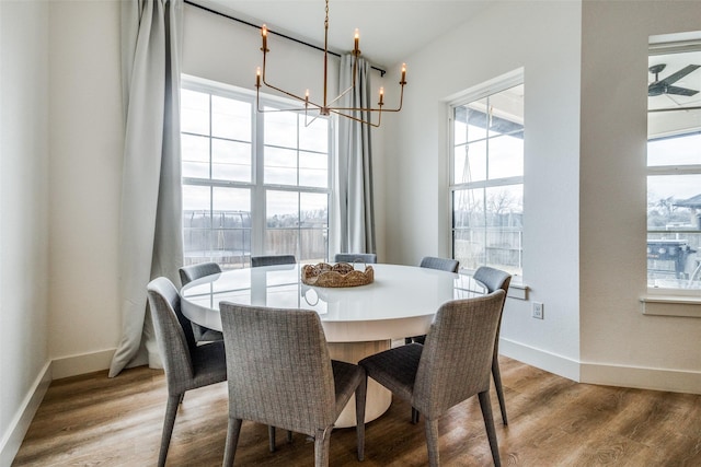 dining area with baseboards, a chandelier, and wood finished floors