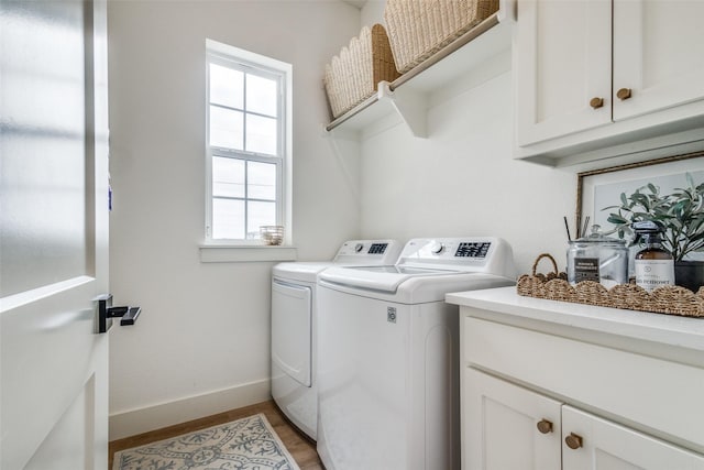 clothes washing area with baseboards, cabinet space, light wood finished floors, and washing machine and clothes dryer