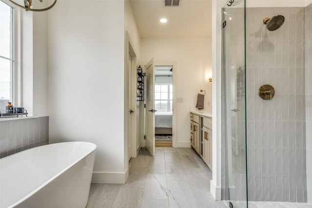 bathroom with ensuite bathroom, vanity, baseboards, a soaking tub, and a tile shower