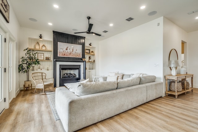 living room featuring recessed lighting, visible vents, a fireplace, and wood finished floors