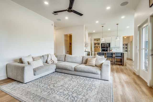 living room with light wood-style flooring, visible vents, ceiling fan, and recessed lighting