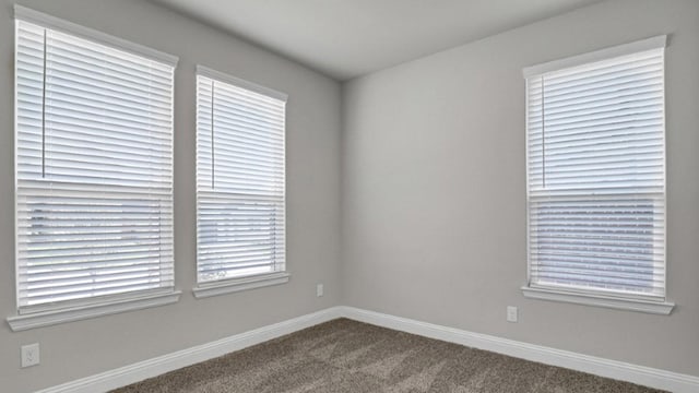 carpeted empty room featuring baseboards