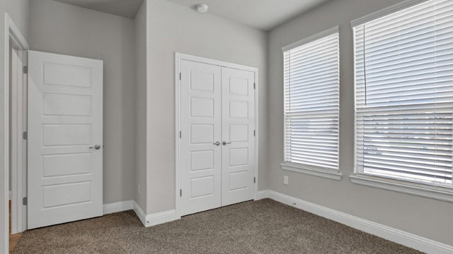 unfurnished bedroom featuring a closet, carpet flooring, and baseboards