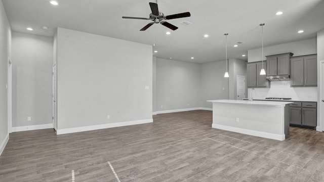 kitchen with open floor plan, light countertops, gray cabinets, and a kitchen island with sink