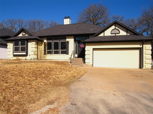 ranch-style house with a shingled roof, concrete driveway, a chimney, an attached garage, and brick siding