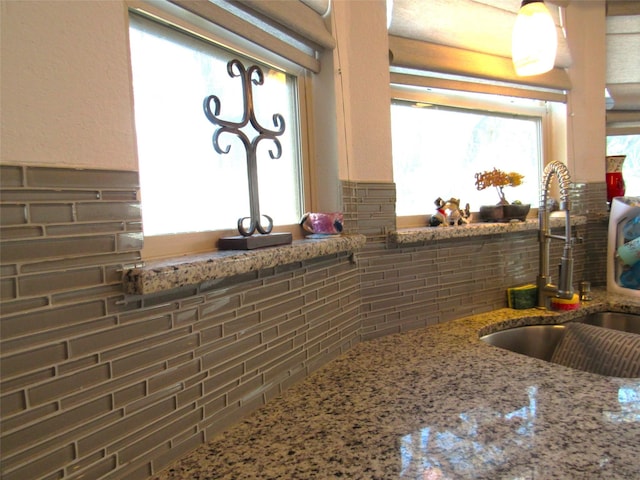 kitchen with stone countertops, a sink, and decorative backsplash