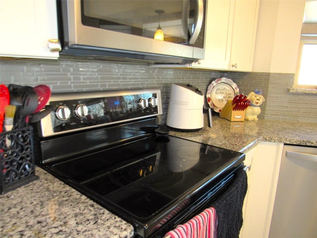 kitchen with dishwashing machine, light stone counters, stainless steel microwave, black / electric stove, and white cabinetry