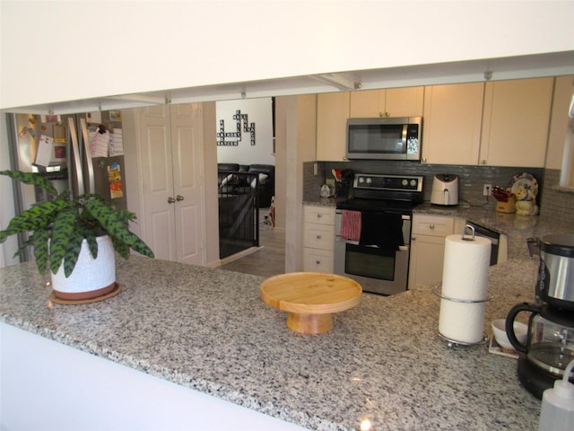 kitchen with stainless steel appliances, light stone counters, a peninsula, and decorative backsplash