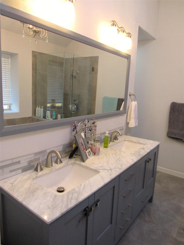 full bathroom with a stall shower, a sink, baseboards, and double vanity