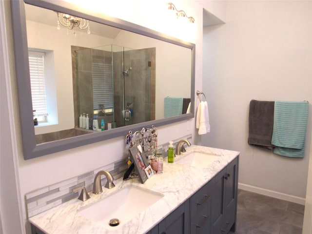 bathroom featuring double vanity, a stall shower, a sink, and baseboards