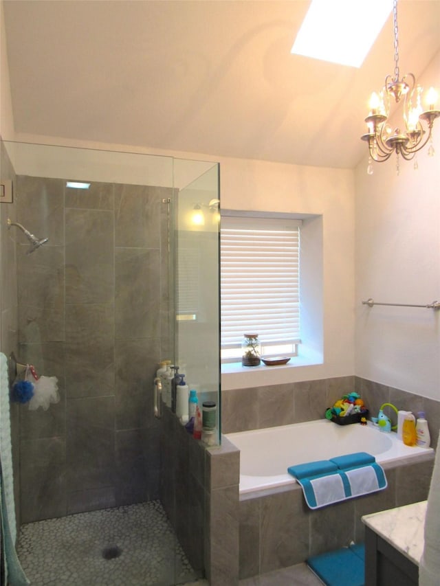 bathroom with a notable chandelier, lofted ceiling with skylight, a stall shower, vanity, and a bath