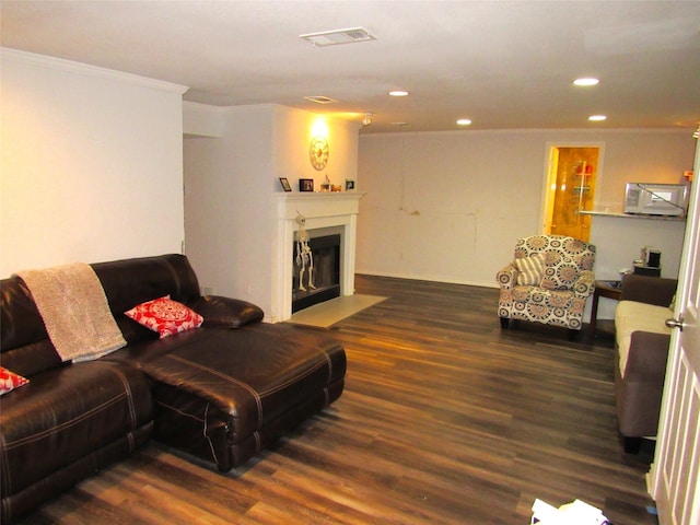 living area with recessed lighting, a fireplace with flush hearth, visible vents, ornamental molding, and dark wood-style floors